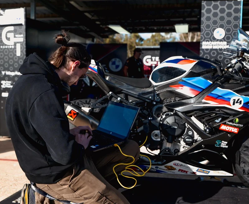 Cody Bower performing data analysis and ECU tuning via laptop in the ASBK pit garage