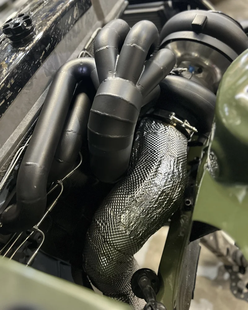 Turbocharger and exhaust manifold with custom multi-layer shielding installed in a Barra-swapped Nissan 180sx.