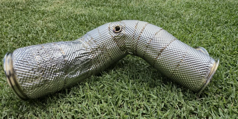 Fully shielded custom exhaust downpipe with integrated O2 sensor bung and multi-layer thermal insulation.