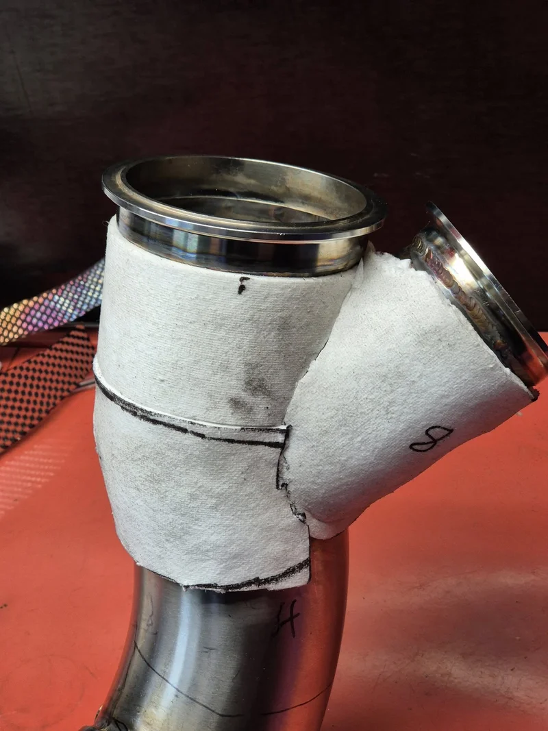 Three sections of ceramic paper attached to the exhaust via adhesive to hold them in place during install. The adhesive will burn off during normal running.